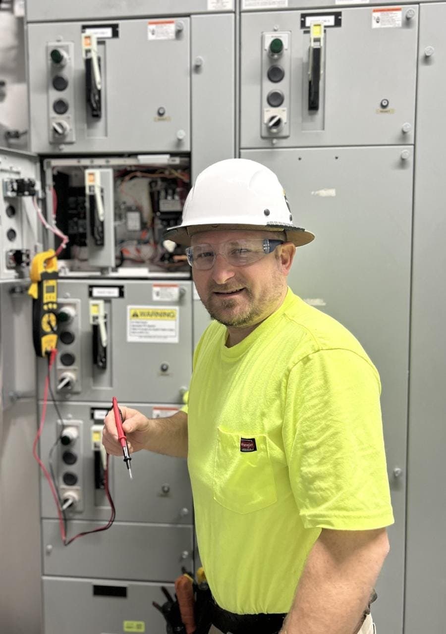 Pate Electrical Services team member standing by electrical equipment